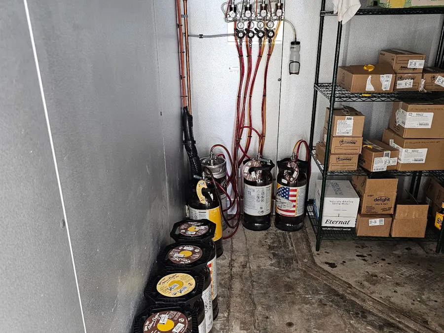 Copper and vinyl beverage lines run from a regulator panel down to nitro coffee kegs