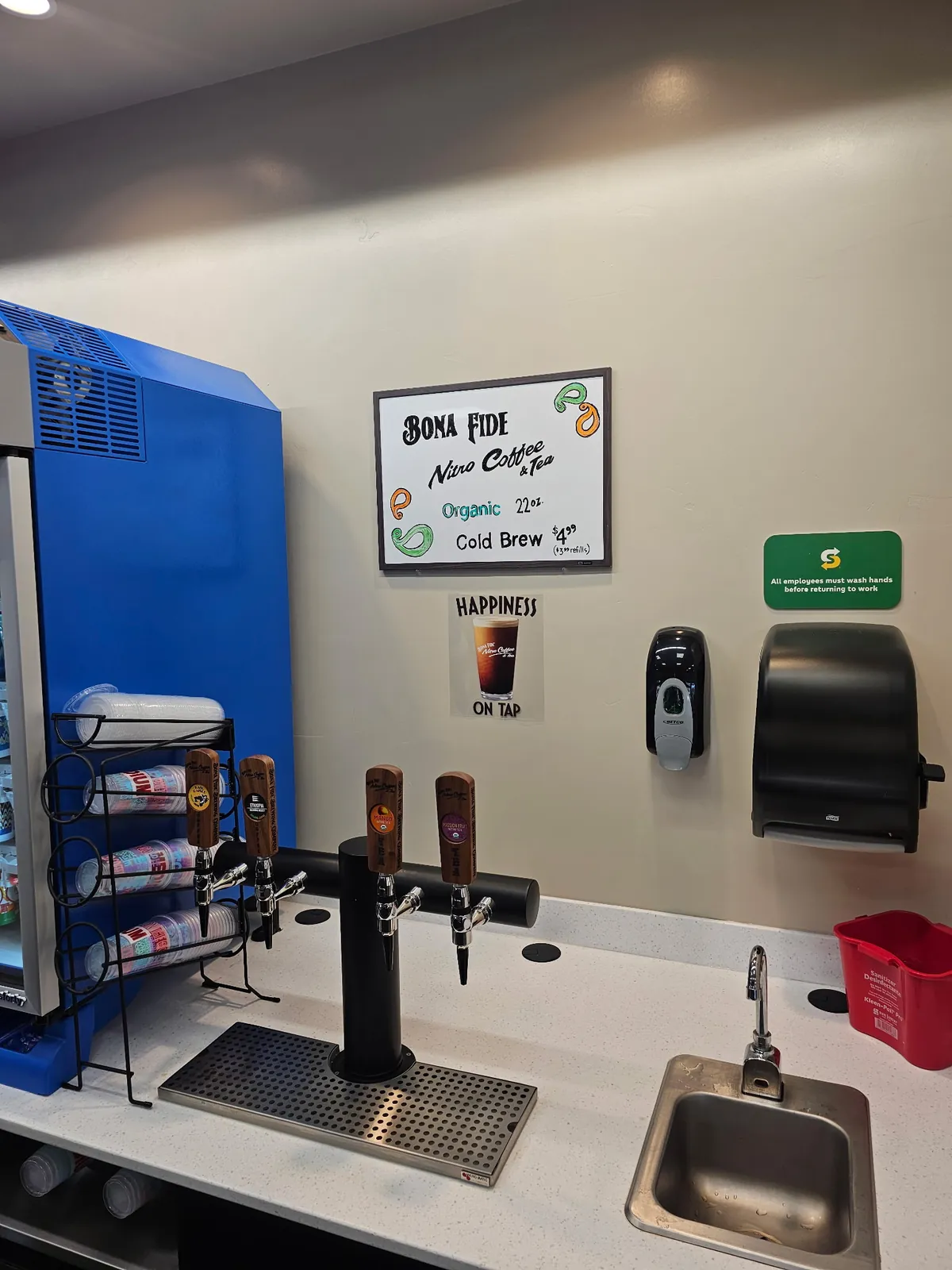 Bona Fide nitro coffee and tea tap tower installed on a counter beside a cup rack