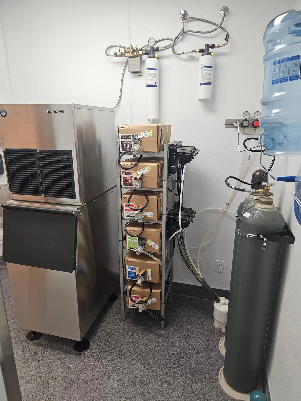 Hoshizaki ice machine beside 3M water filtration in a Cava back room