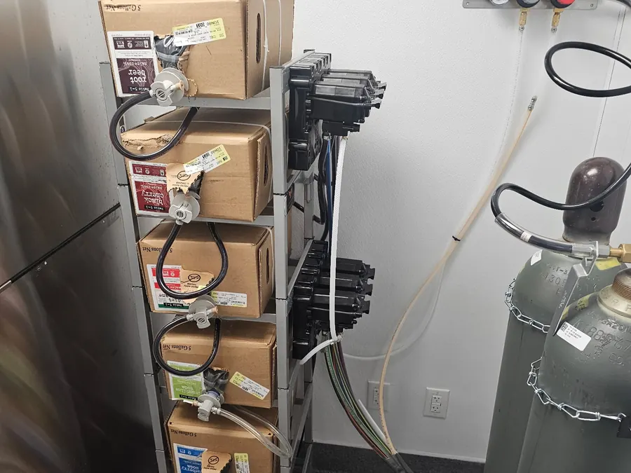 Bag in box syrup rack with pumps and a CO2 cylinder installed in a Cava back room